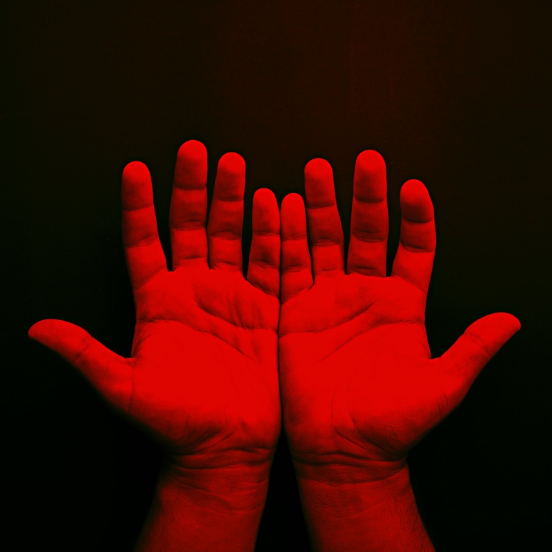Jovian Outpost artwork: two open hands lit in red